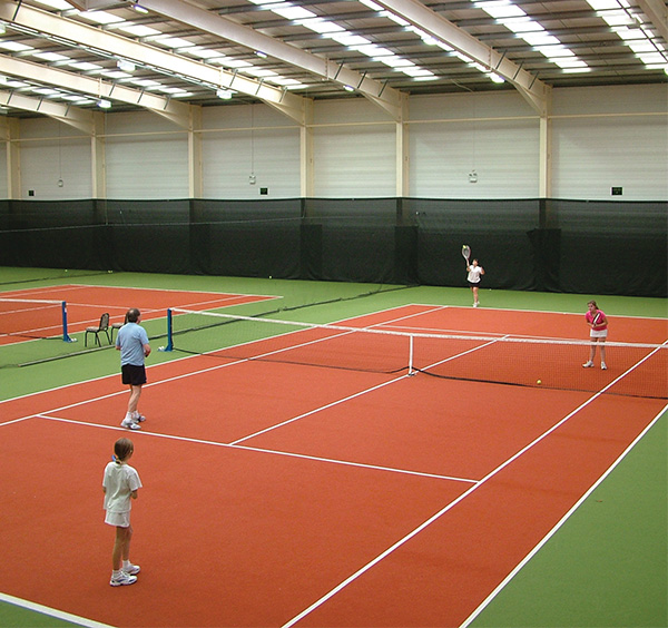 4 people playing a doubles match on an indoor tennis court